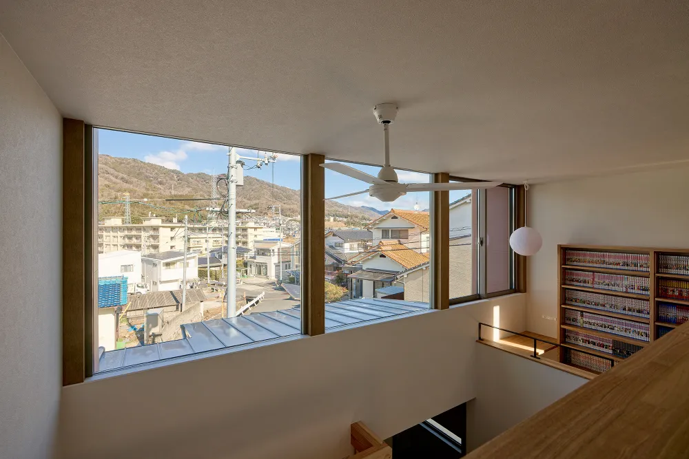 高低差のある景色と青空を 大きな窓から眺める家