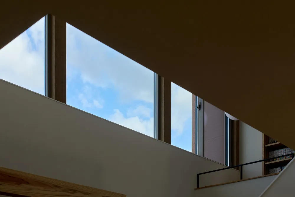 高低差のある景色と青空を 大きな窓から眺める家